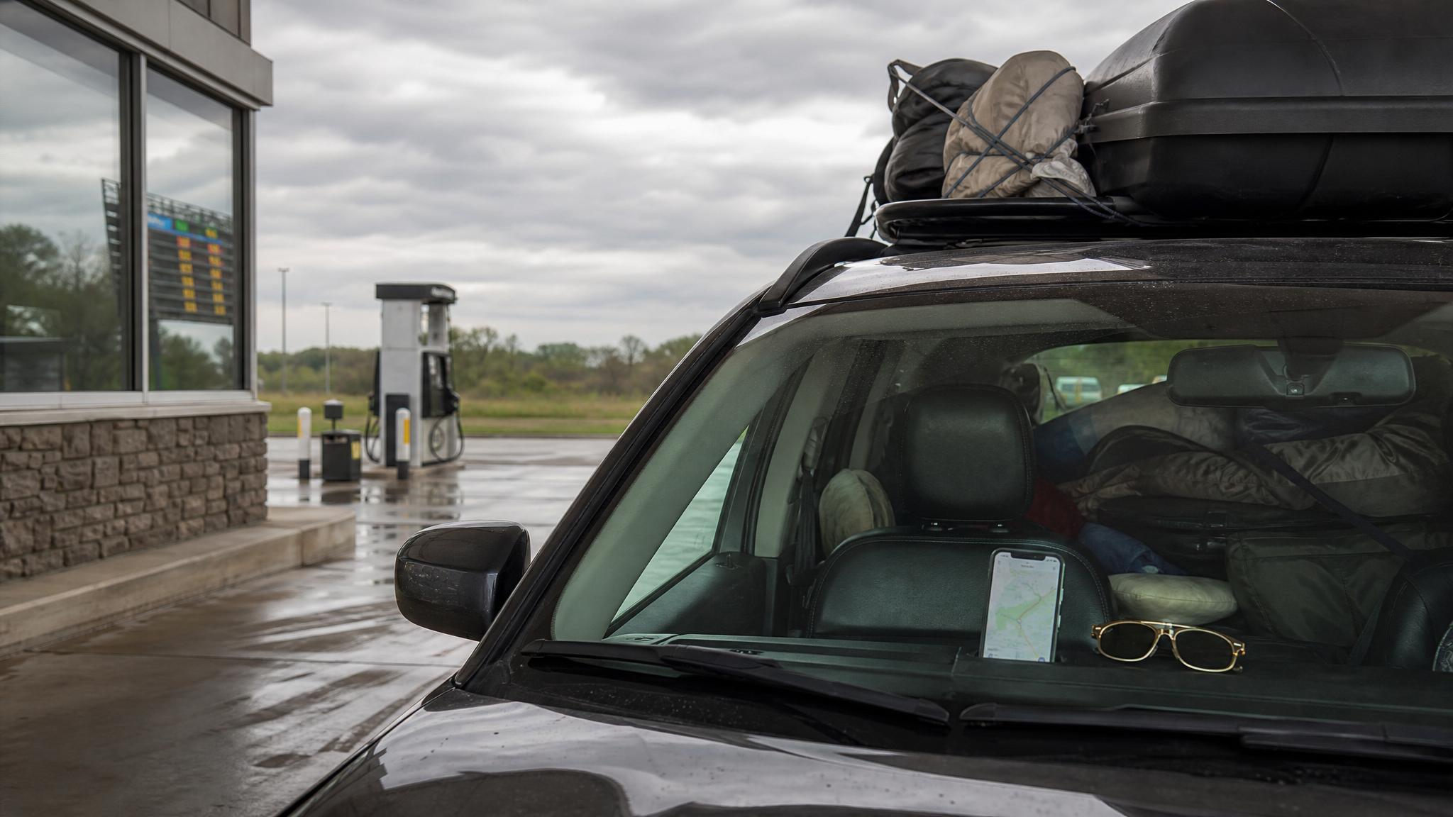 Packed car at a gas station before a Memorial Day road trip with cloudy travel weather ahead