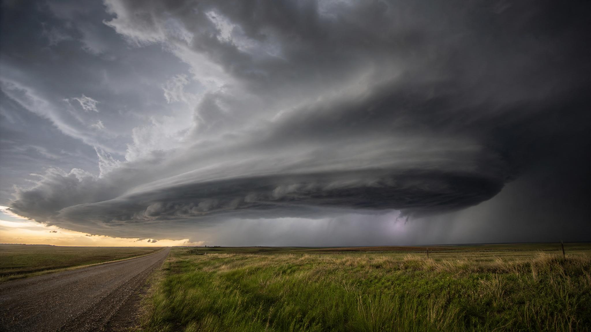 Dark supercell storm clouds over open Great Plains farmland near a rural road